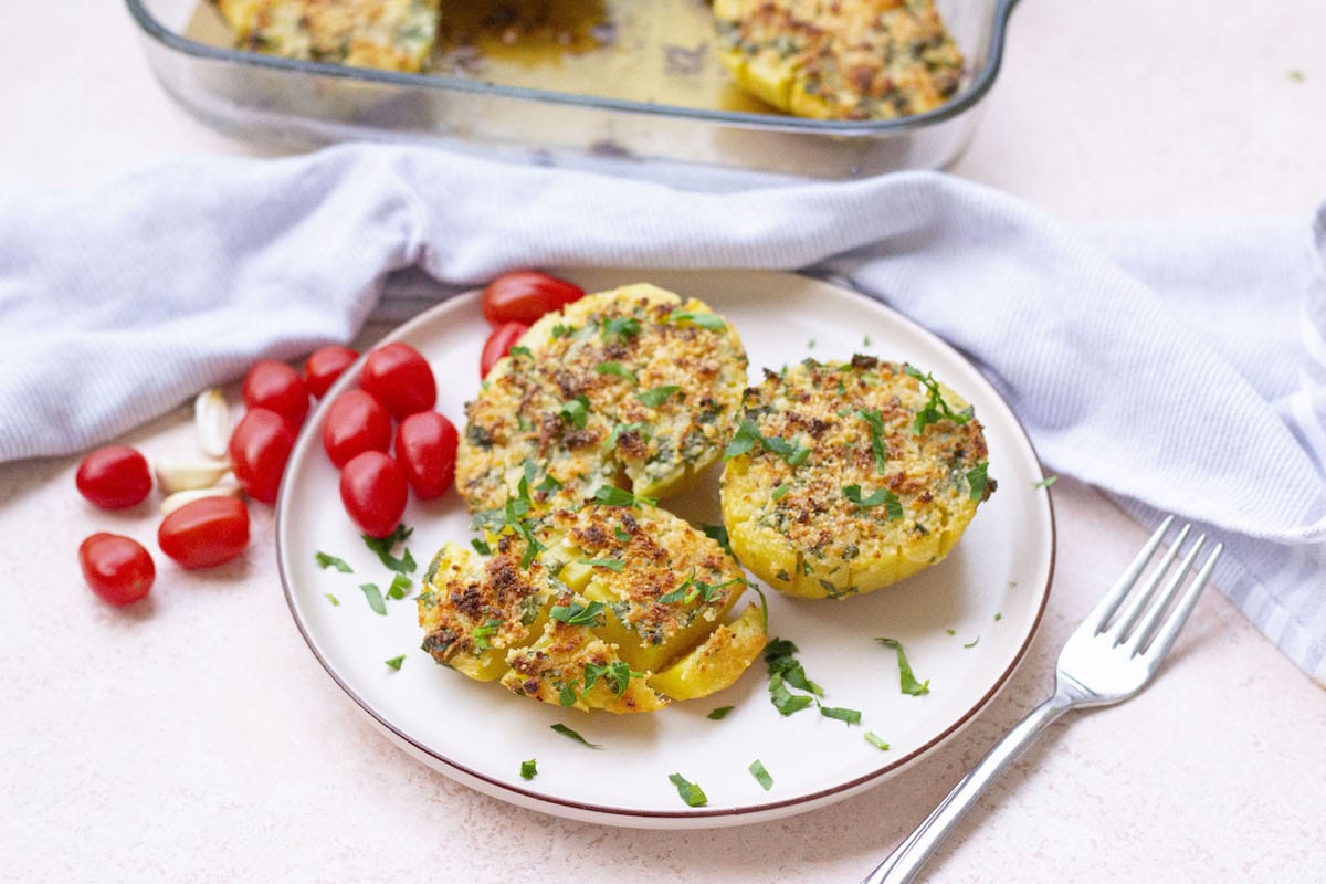 Crispy roasted potatoes with a golden parmesan crust on a white plate.