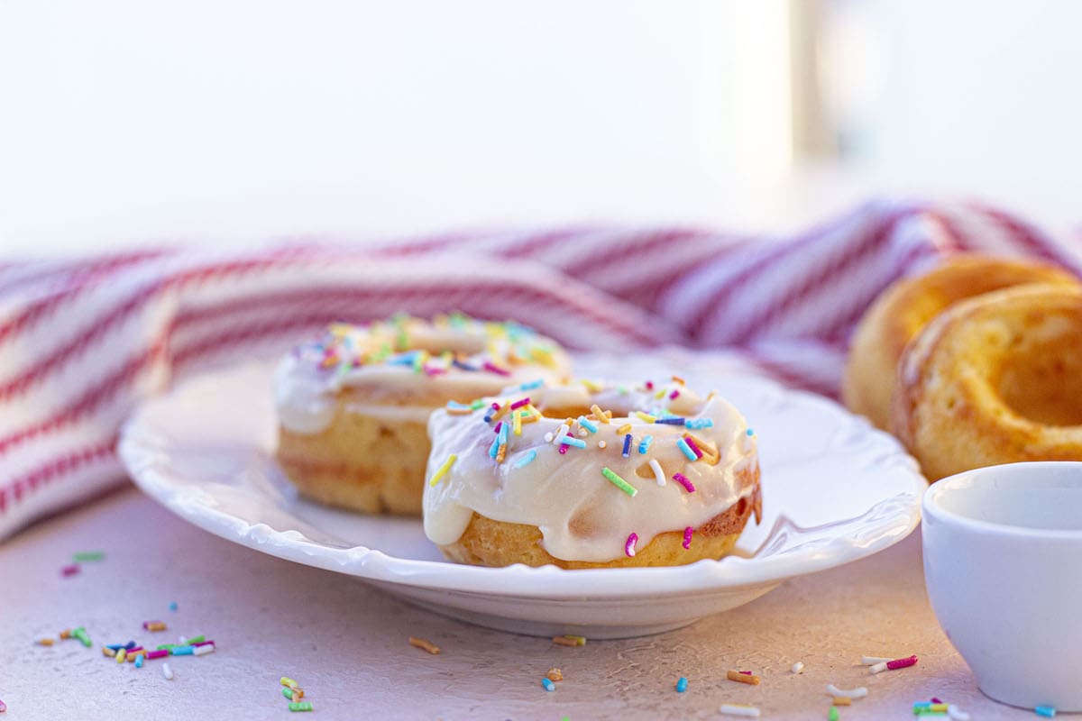 Two protein donuts on a plate with sprinkles.