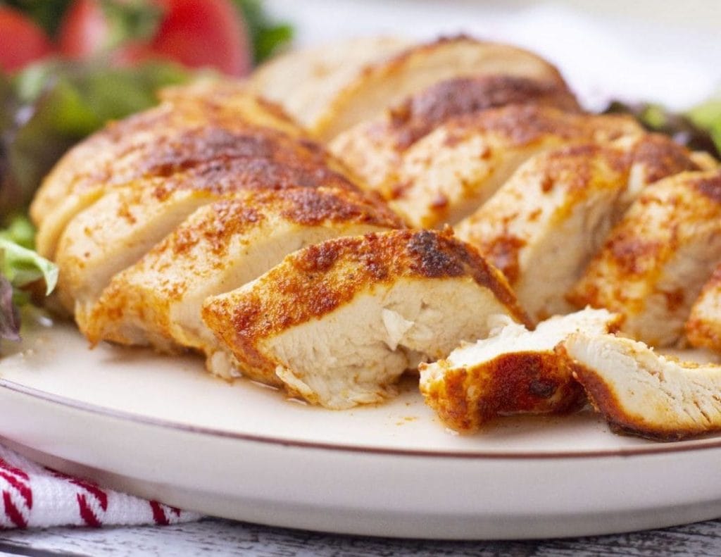 Grilled chicken breast on a plate with salad.