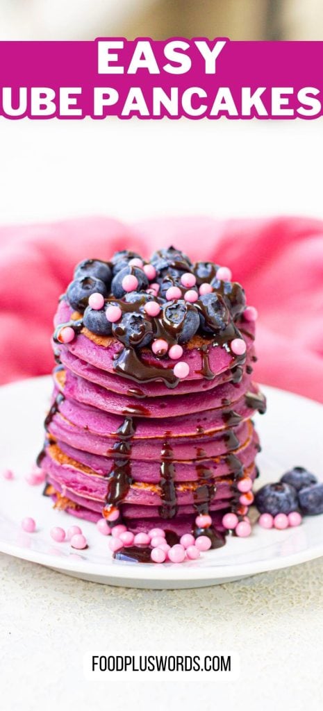 A stack of purple pancakes topped with blueberries and icing.