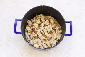 A Dutch oven filled with a mixture of apples and oats.
