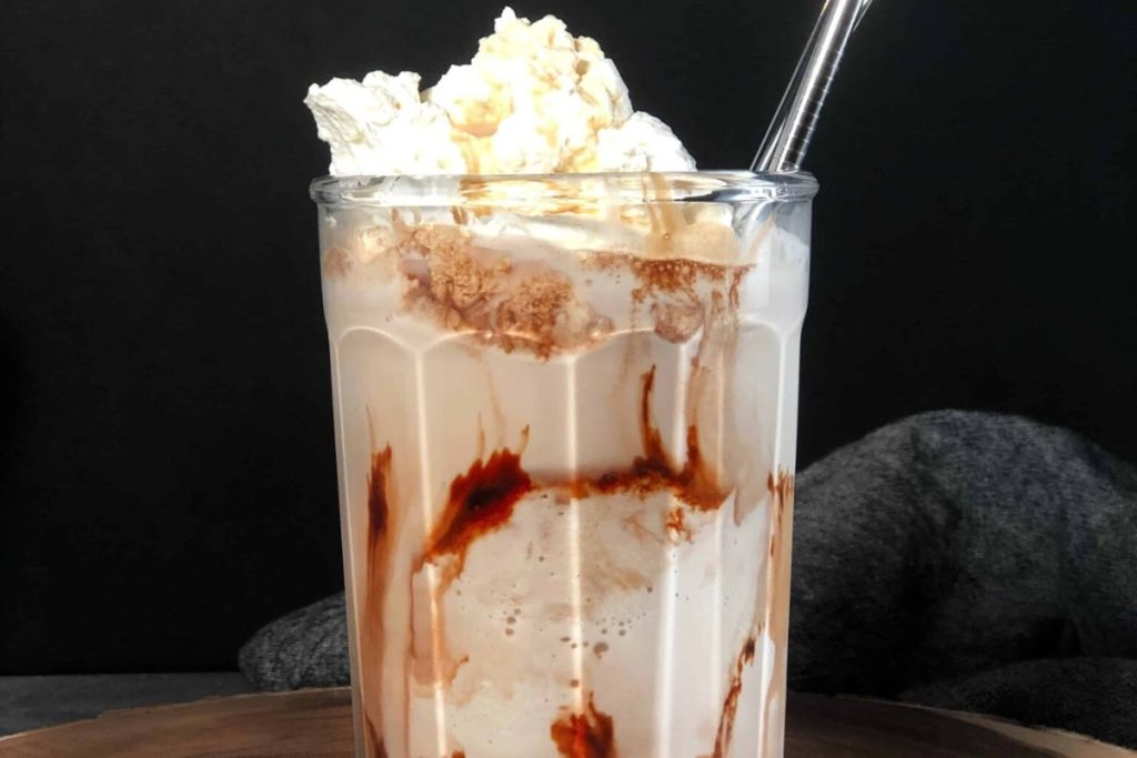 A chocolate milkshake with whipped cream and chocolate syrup.