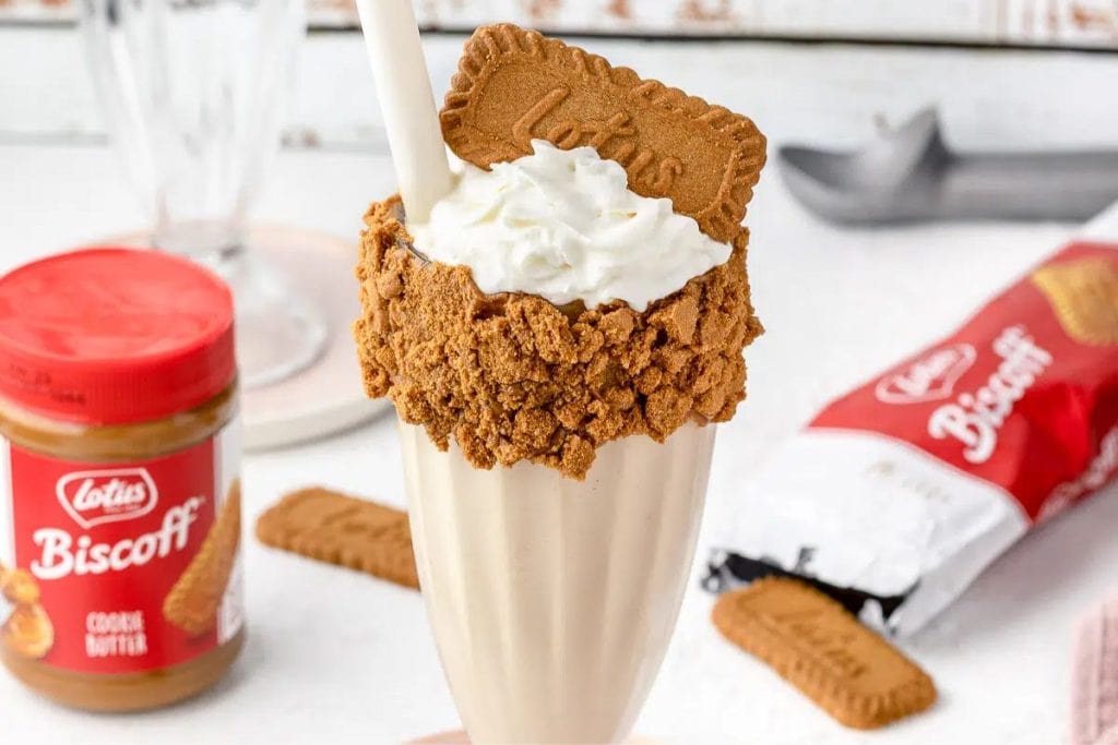 A milkshake with whipped cream and biscuits.