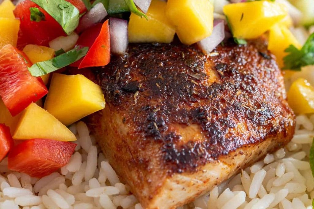 A plate of rice and fish with mango salsa.
