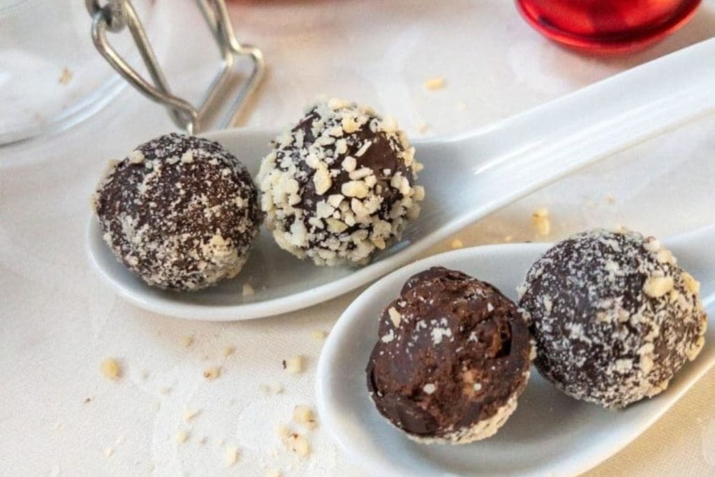 Three spoons filled with chocolate truffles on a table.