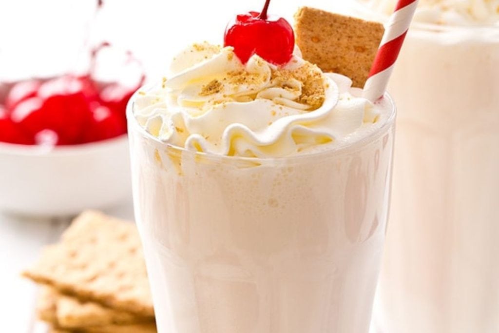 A milkshake with whipped cream and a cherry on top.
