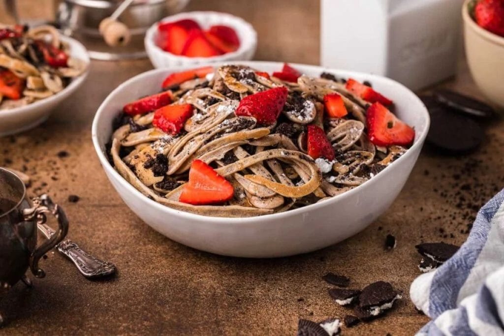 A bowl of pasta with strawberries and chocolate.