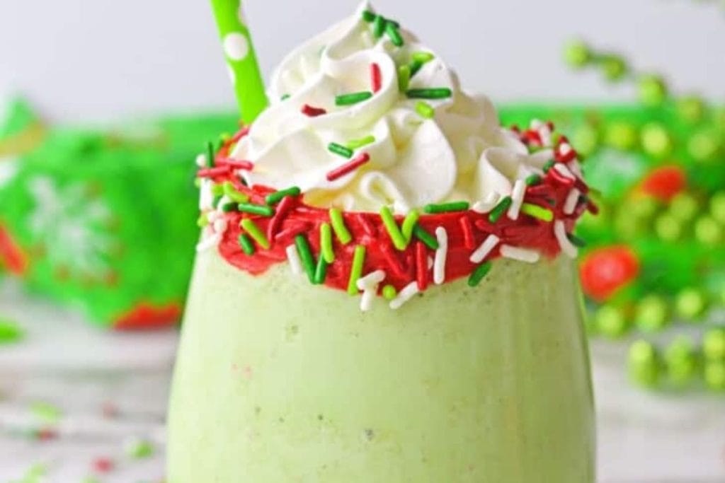 A green smoothie with whipped cream and green sprinkles.