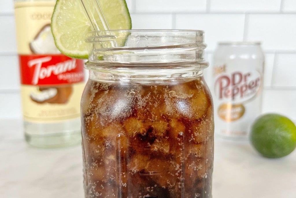 A mason jar filled with cola and a lime wedge.