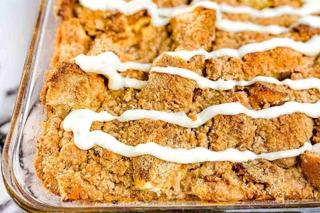 Apple cinnamon bread pudding in a baking dish with icing.