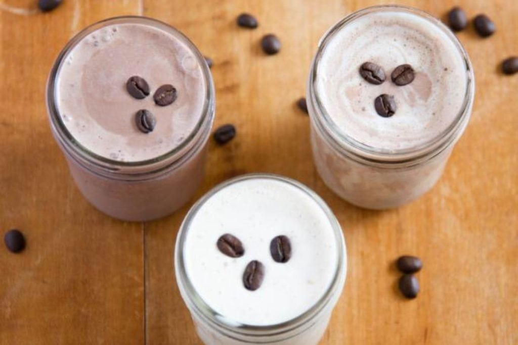 Three jars of coffee and chocolate shakes on a wooden table.
