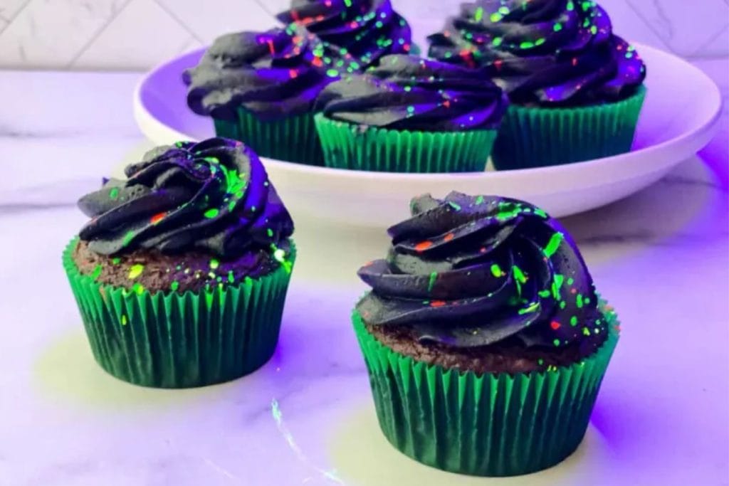 Dark chocolate cupcakes with green and purple sprinkles.