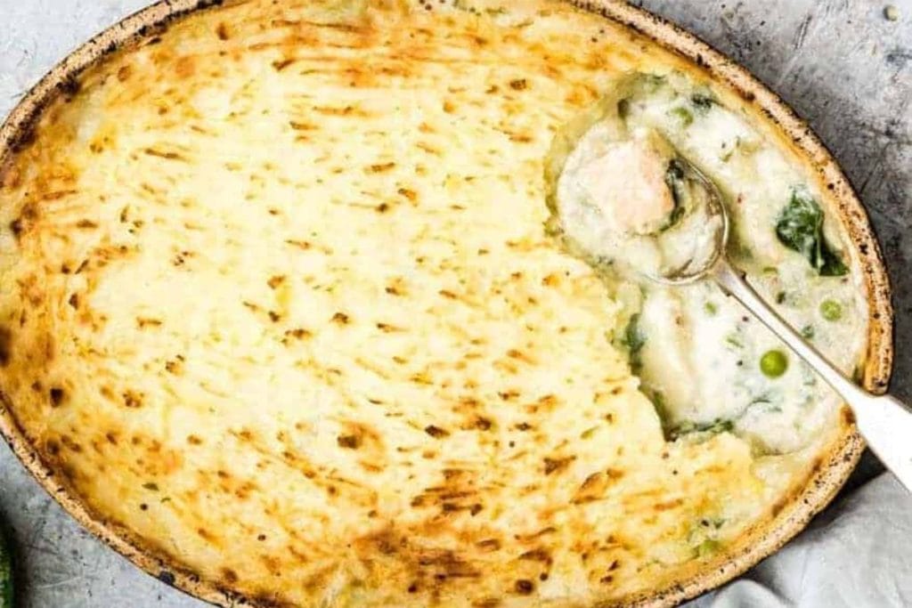 A dish of chicken and spinach pie with a spoon.