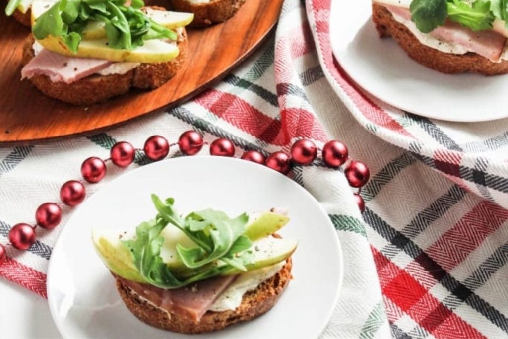 Two slices of toast with ham and arugula.