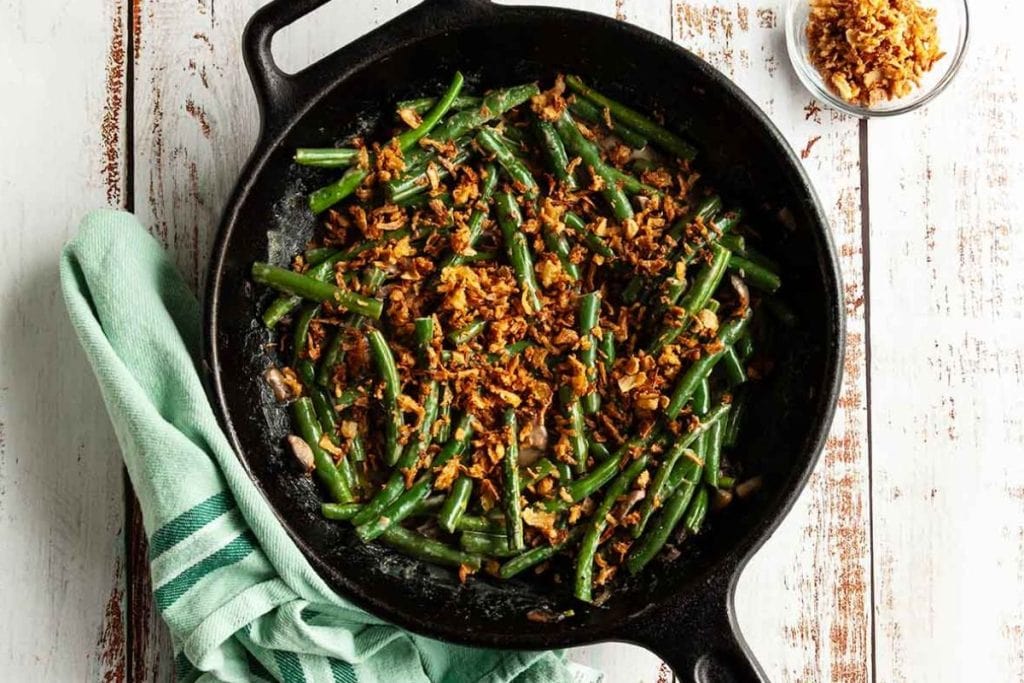 A skillet filled with green beans and nuts.