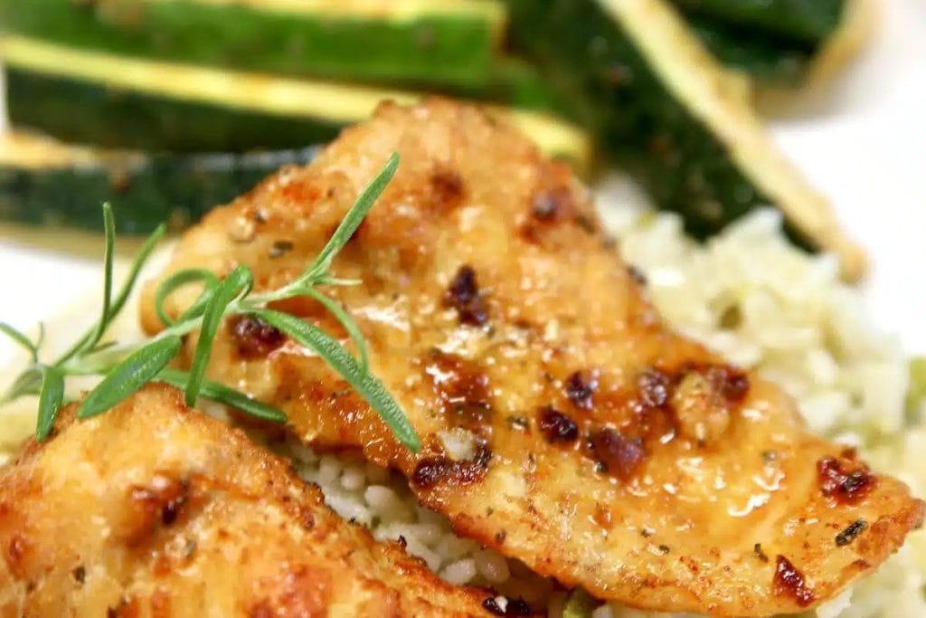 A plate of rice and chicken with sprigs of rosemary.