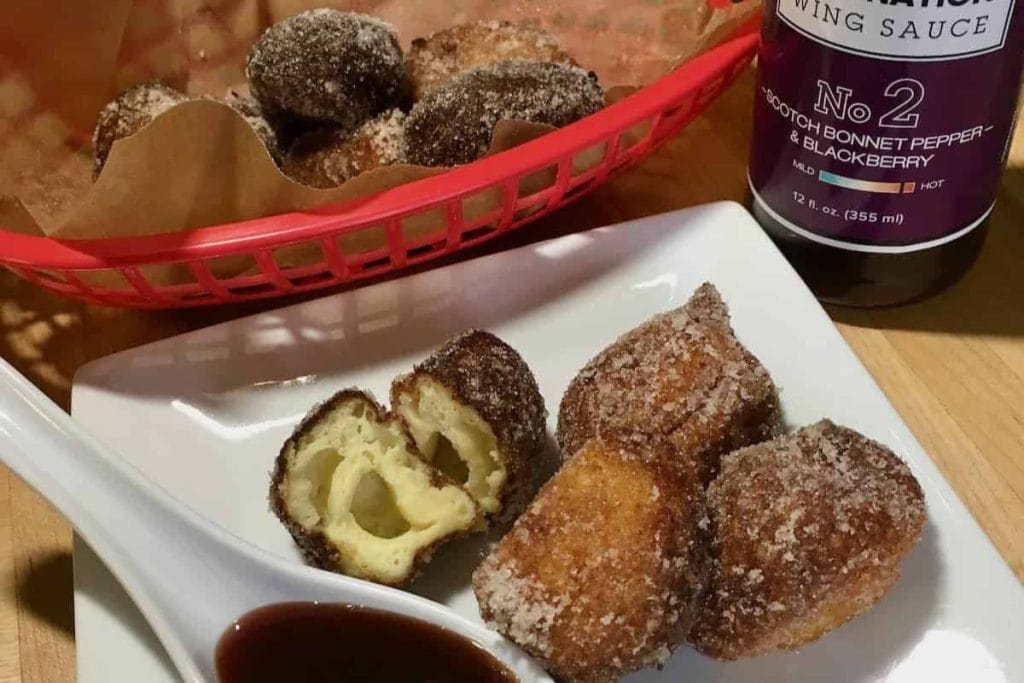Fried doughnuts with dipping sauce on a plate.