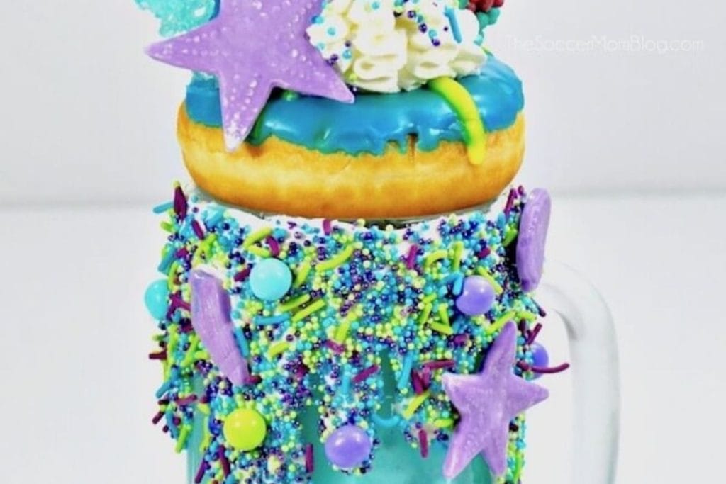 A mermaid themed coffee mug with donuts and sprinkles.