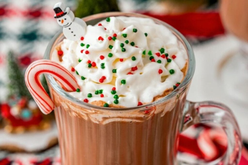A cup of hot chocolate with whipped cream and candy canes.