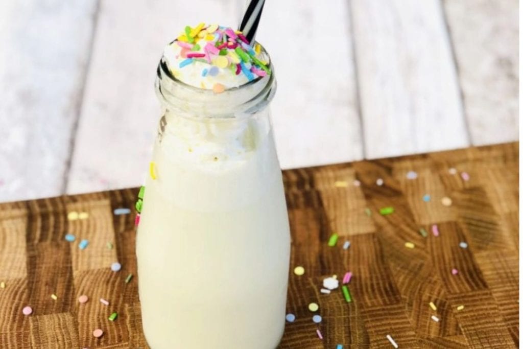 A bottle of milk with sprinkles and a straw.