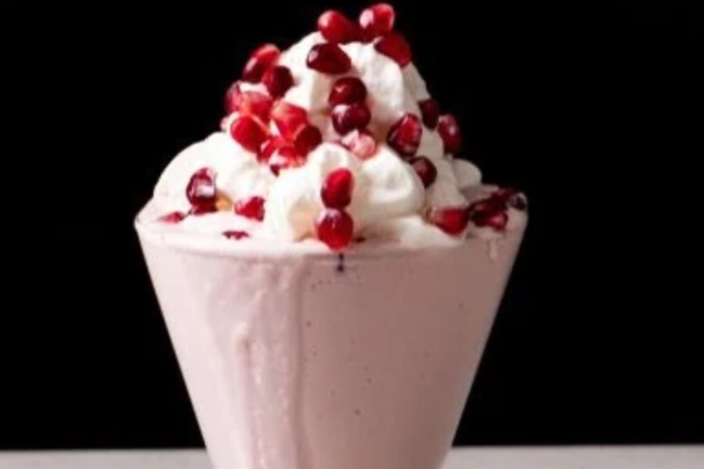 A pomegranate milkshake with whipped cream and pomegranate.