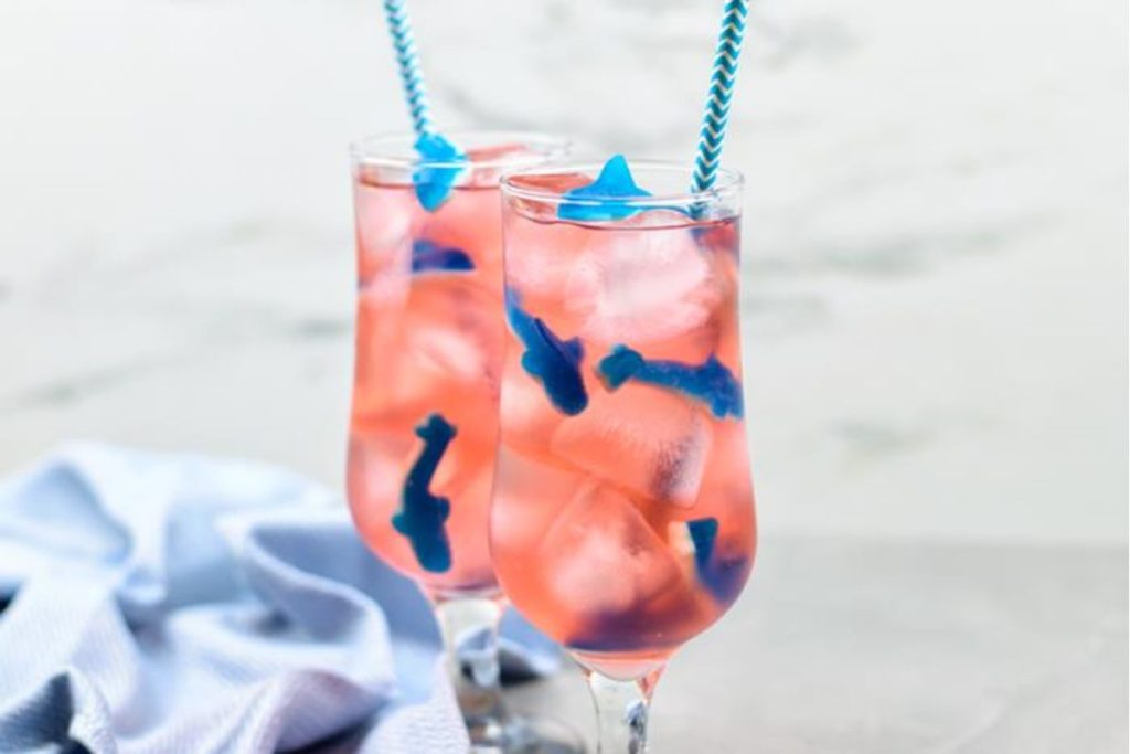 Two glasses of pink and blue drinks with blue striped straws.