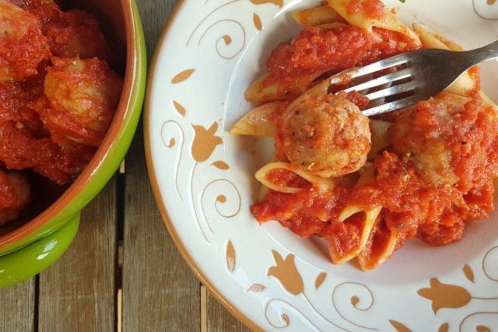 A plate of pasta with meatballs and sauce.