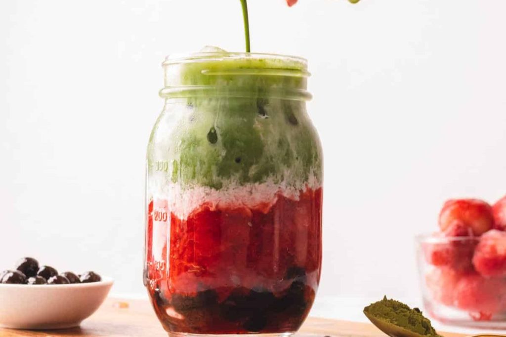 A mason jar with a strawberry, blueberry, and blackberry smoothie.
