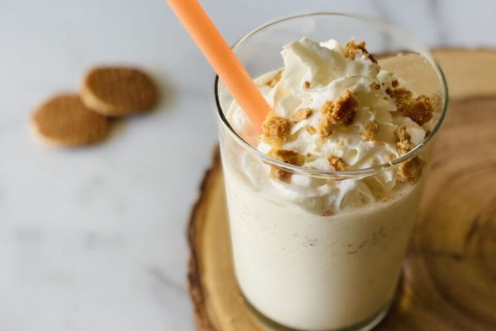 A milkshake with whipped cream and a straw.