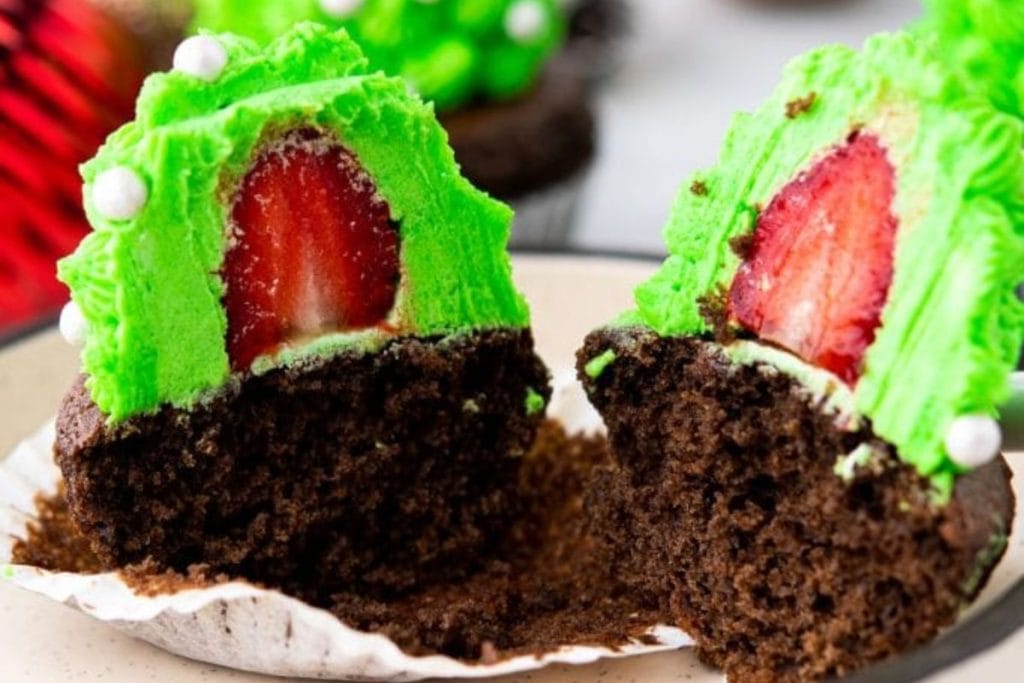 This cupcake recipe features two chocolate cupcakes with a delightful surprise inside - a fresh strawberry! Topped with vibrant green frosting, these cupcakes are the perfect treat for any occasion.