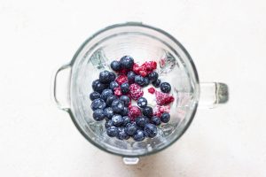 Berries and milkshake recipe blended on a white surface.