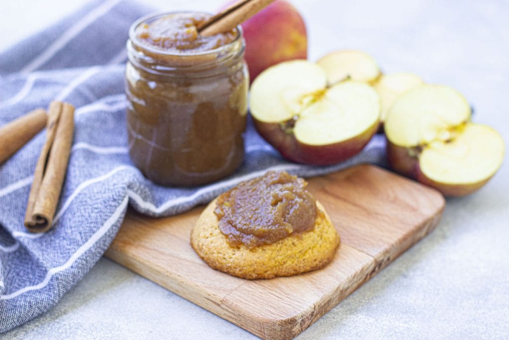 Apple butter on a cookie on a wooden cutting board with cinnamon sticks, perfect for your apple butter recipe.
