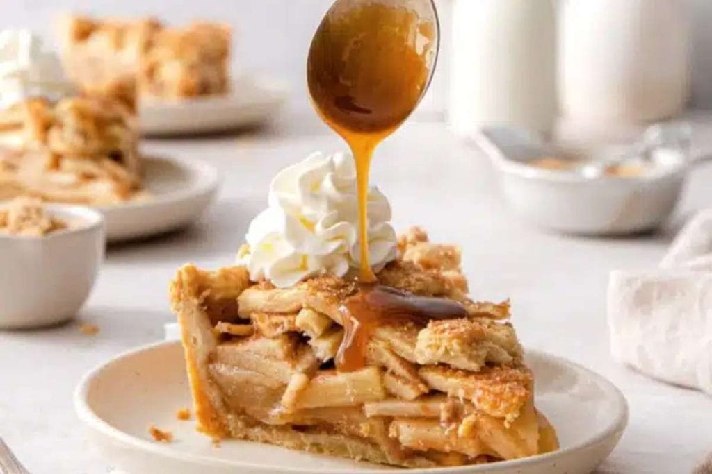 A slice of apple pie being drizzled with caramel sauce in a mesmerizing display of deliciousness.