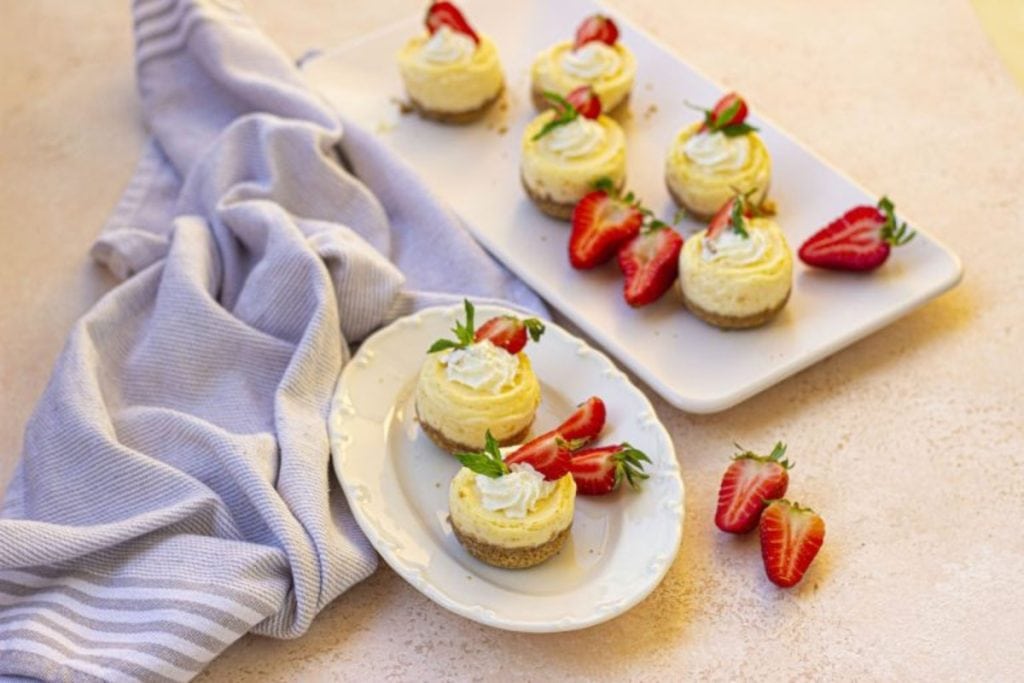 Mini cheesecakes with strawberries on a plate.