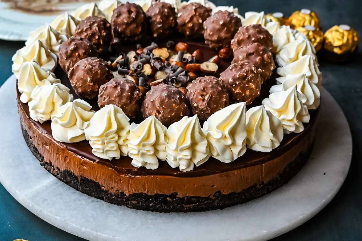 A chocolate cake topped with chocolate balls and whipped cream is a delightful treat for any chocoholic.