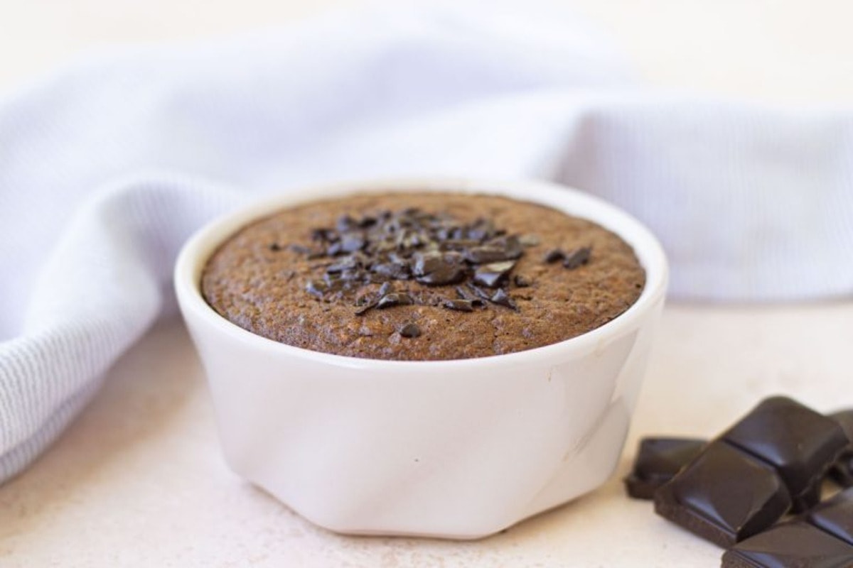 Chocolate pudding in a white cup with chocolate chips.