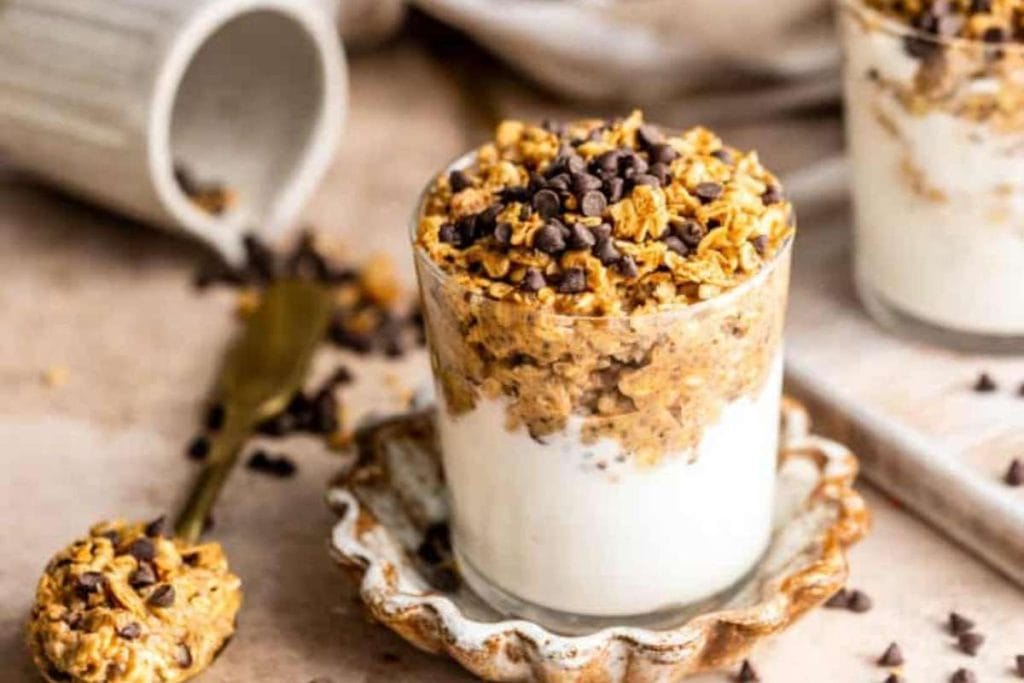 A glass of overnight oats with granola and chocolate chips.