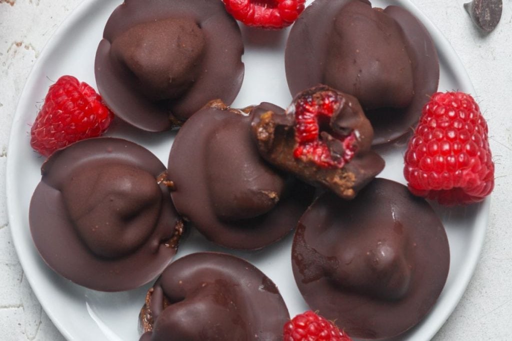 Valentines snacks: chocolate covered raspberries on a white plate.