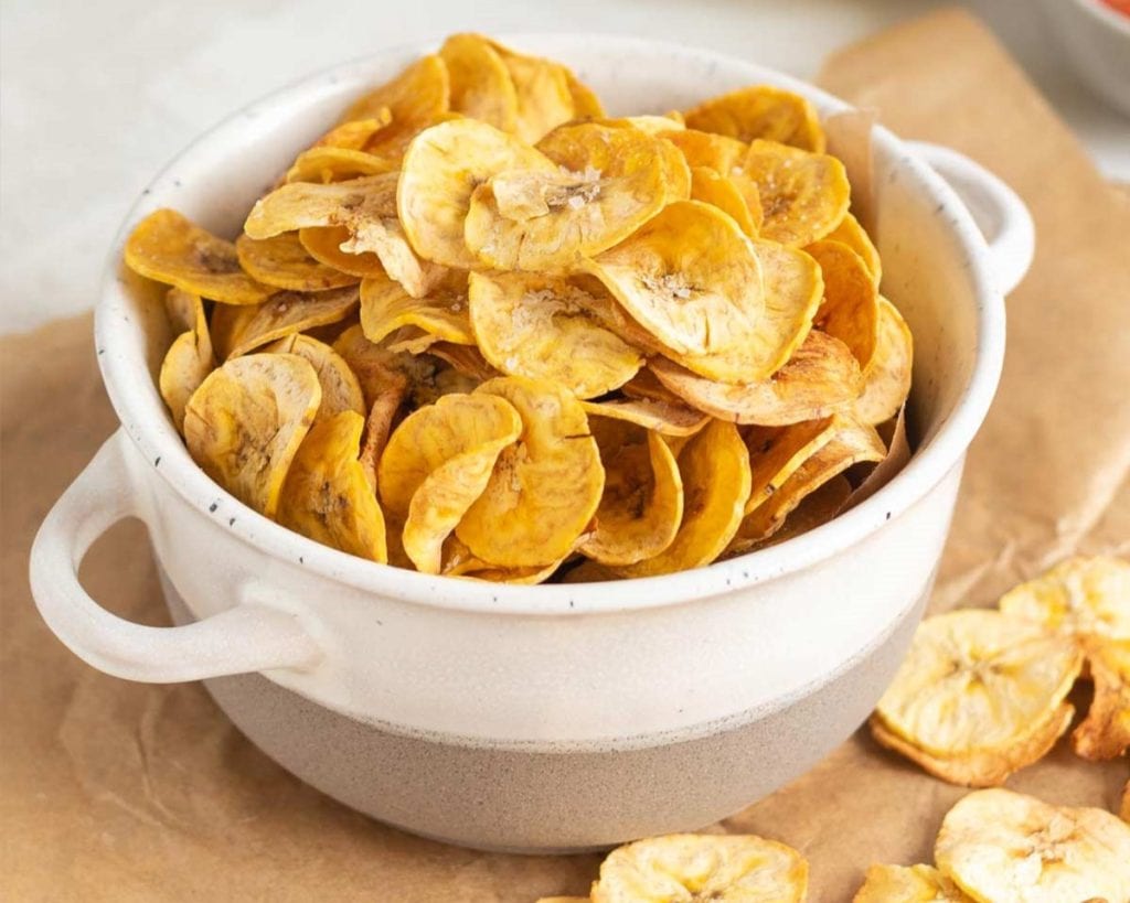 A bowl of healthy dried banana slices on a table.