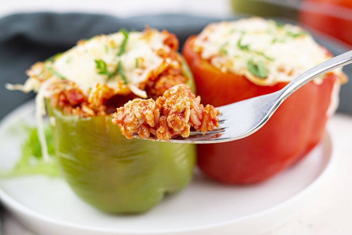 Stuffed bell peppers served on a plate, with a forkful of the filling lifted out to show the texture.