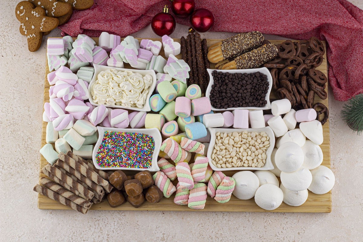 Assorted confectionery and cookies on a wooden tray with holiday decorations.