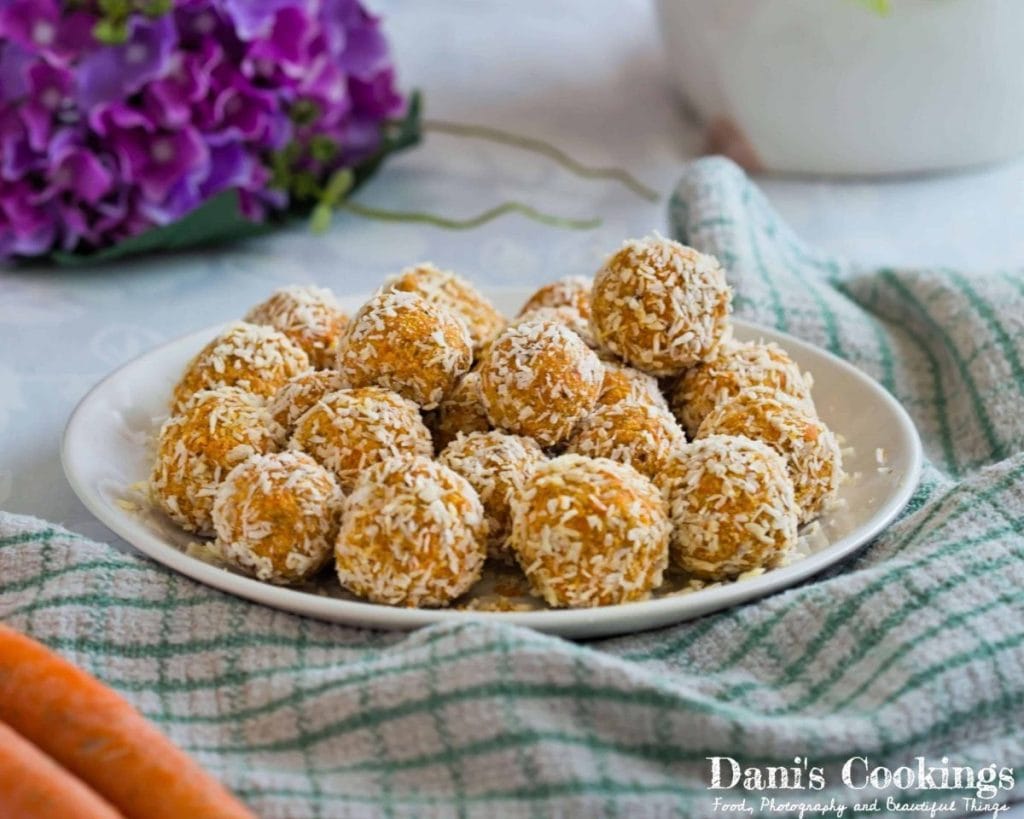 Plate of healthy carrot coconut balls garnished with shredded coconut on a table.