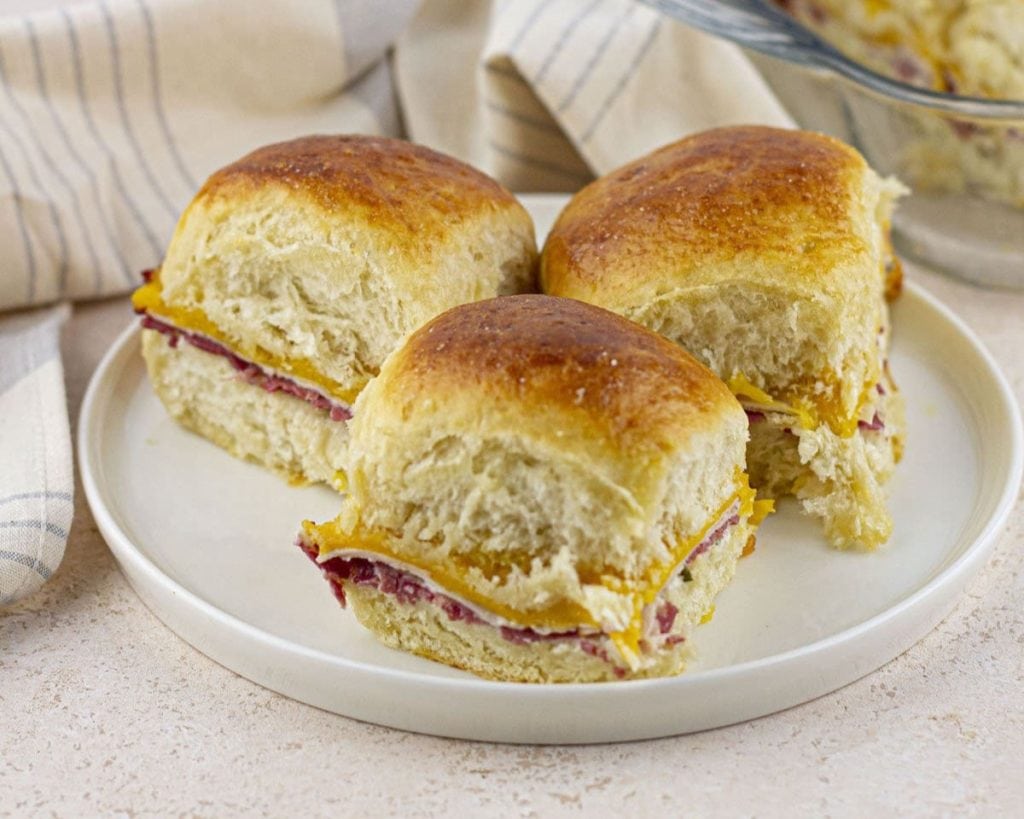 Freshly baked ham and cheese sandwiches on a white plate, perfect for last-minute dinner ideas.