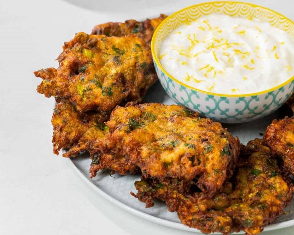 Healthy fried vegetable fritters served with a side of yogurt sauce.
