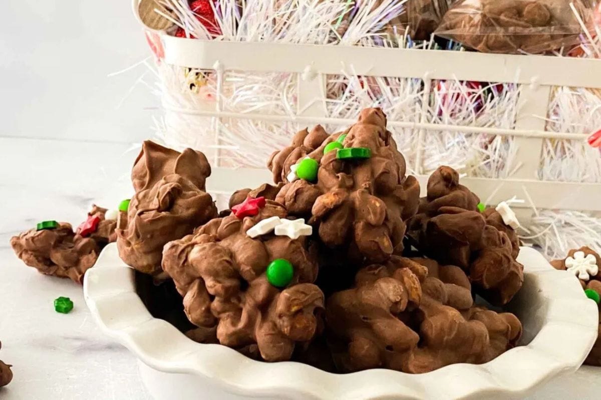 A bowl of chocolate clusters with colorful sprinkles, set in front of a white basket filled with decorative items.
