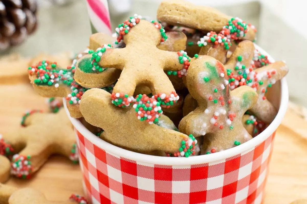 A red and white checkered bowl filled with gingerbread cookies, some decorated with green, red, and white sprinkles, shaped like people.