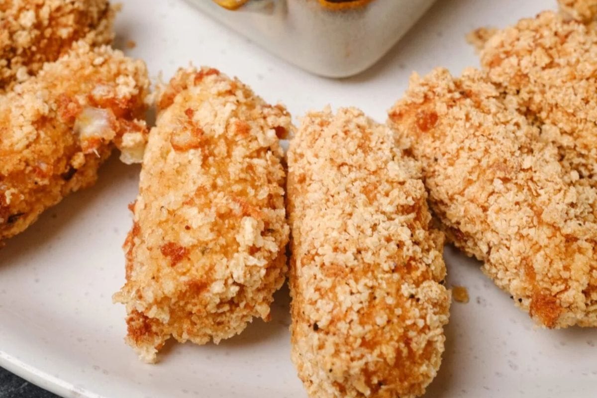 Four pieces of breaded and fried food are placed on a white plate, offering easy tailgate snacks for any gathering.
