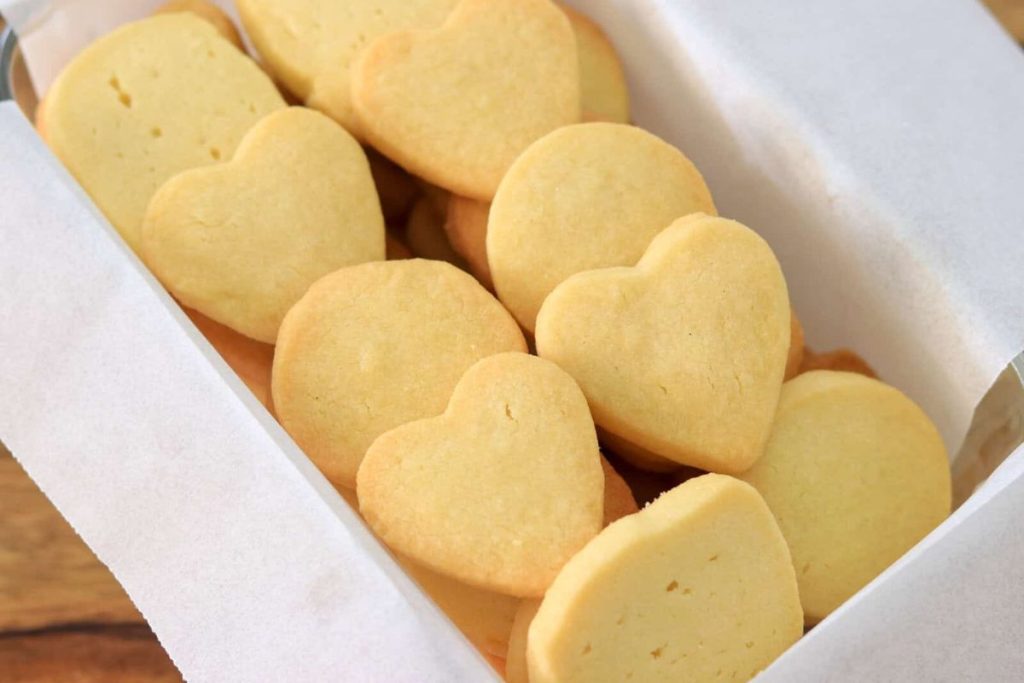 Heart-shaped and round cookies arranged in a white paper-lined box.