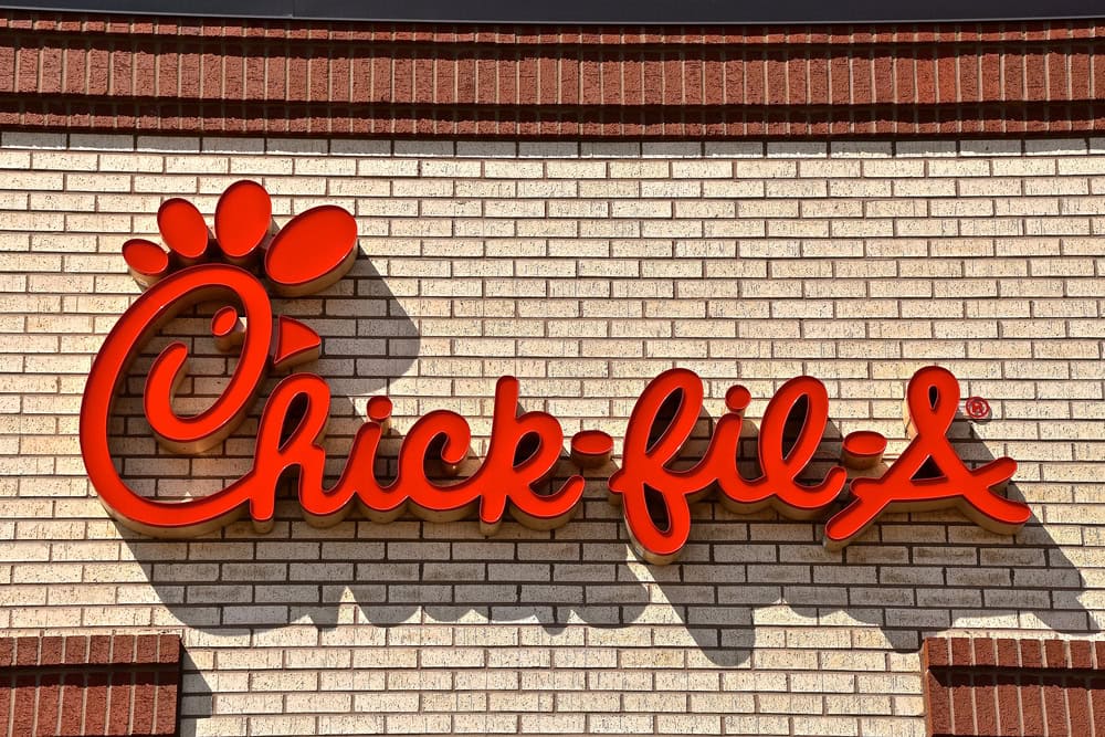 Red Chick-fil-A logo on a beige brick wall.
