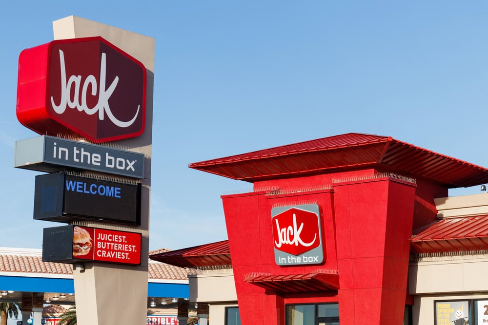 Jack in the Box restaurant with red signage and logo, including phrases like "Juiciest. Butteriest. Craviest." and "Welcome" on smaller signs beneath the main logo.